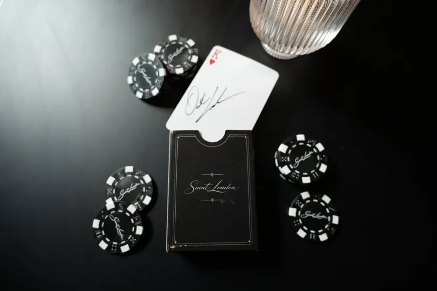 Saint London card case, a signed king of hearts and branded chips on a dark table