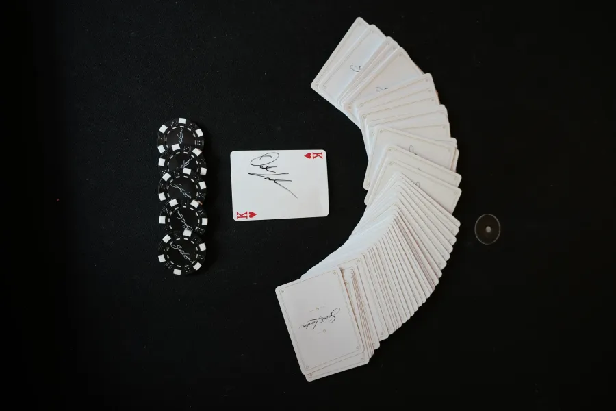Saint London deck fanned in an arc beside a stack of branded chips and a signed king of hearts