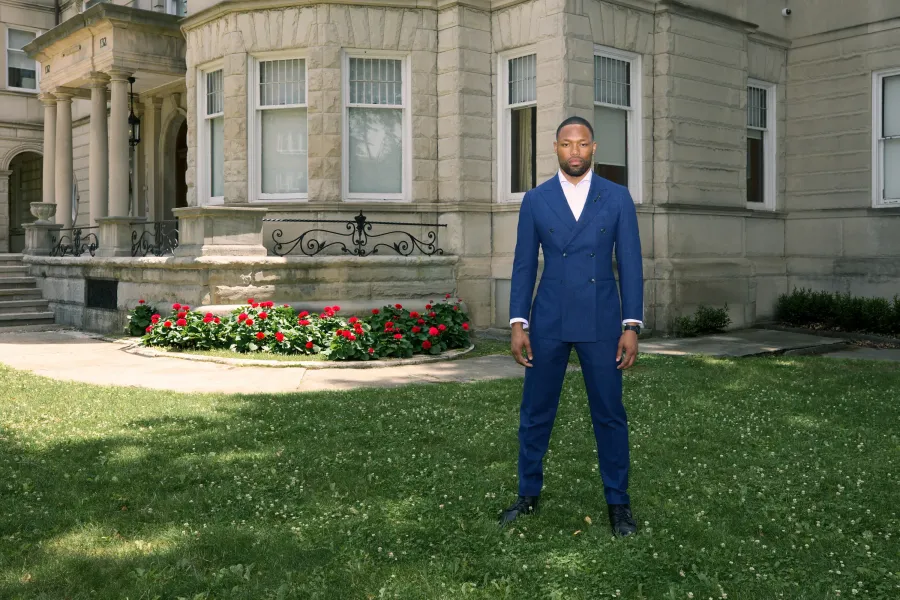Navy double-breasted suit on the lawn of a stone manor house