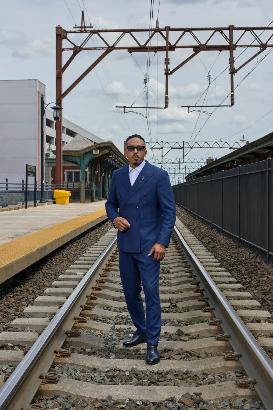 Navy double-breasted suit on the railway tracks